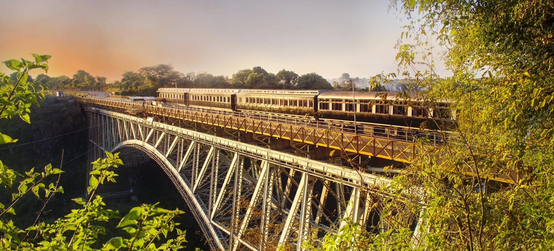 Bushtacks dinner train crossing the Victoria Falls bridge at sunset.